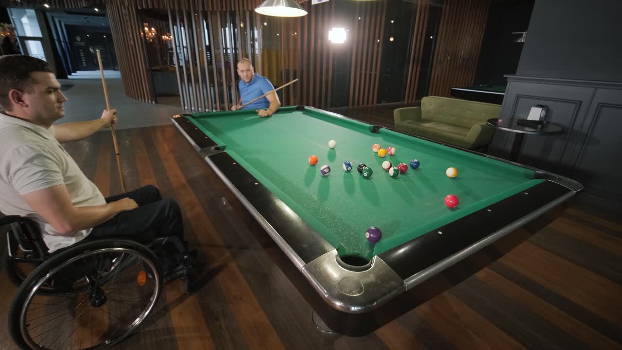 Adult men with disabilities in a wheelchair play billiards in the club