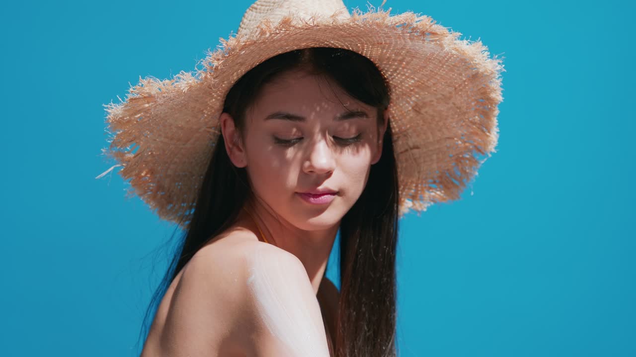 Young woman putting sunscreen on shoulder smiles for the camera