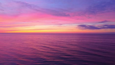 Agua-De-Mar-Tranquila-Y-Puesta-De-Sol-De-Colores-Vivos,-Vista-De-Descenso-De-Drones-Aéreos