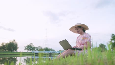 adult woman sitting on lawn working with computer