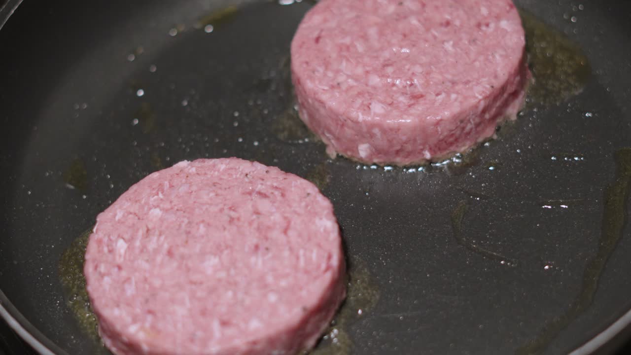 Two Raw Aberdeen Angus Beef Burgers Cooking on High Heat in Frying Pan. Delicious Meat Patties Sizzling in Slow Motion. High Fat Food Clip