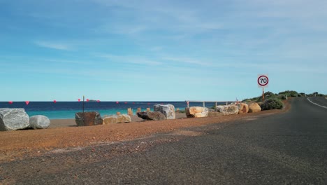 Carretera-Marginal-En-La-Costa-De-Cabo-Leeuwin-Con-Aguas-De-Playa-Paradisíaca-Y-Señal-De-Límite-De-Velocidad,-Australia