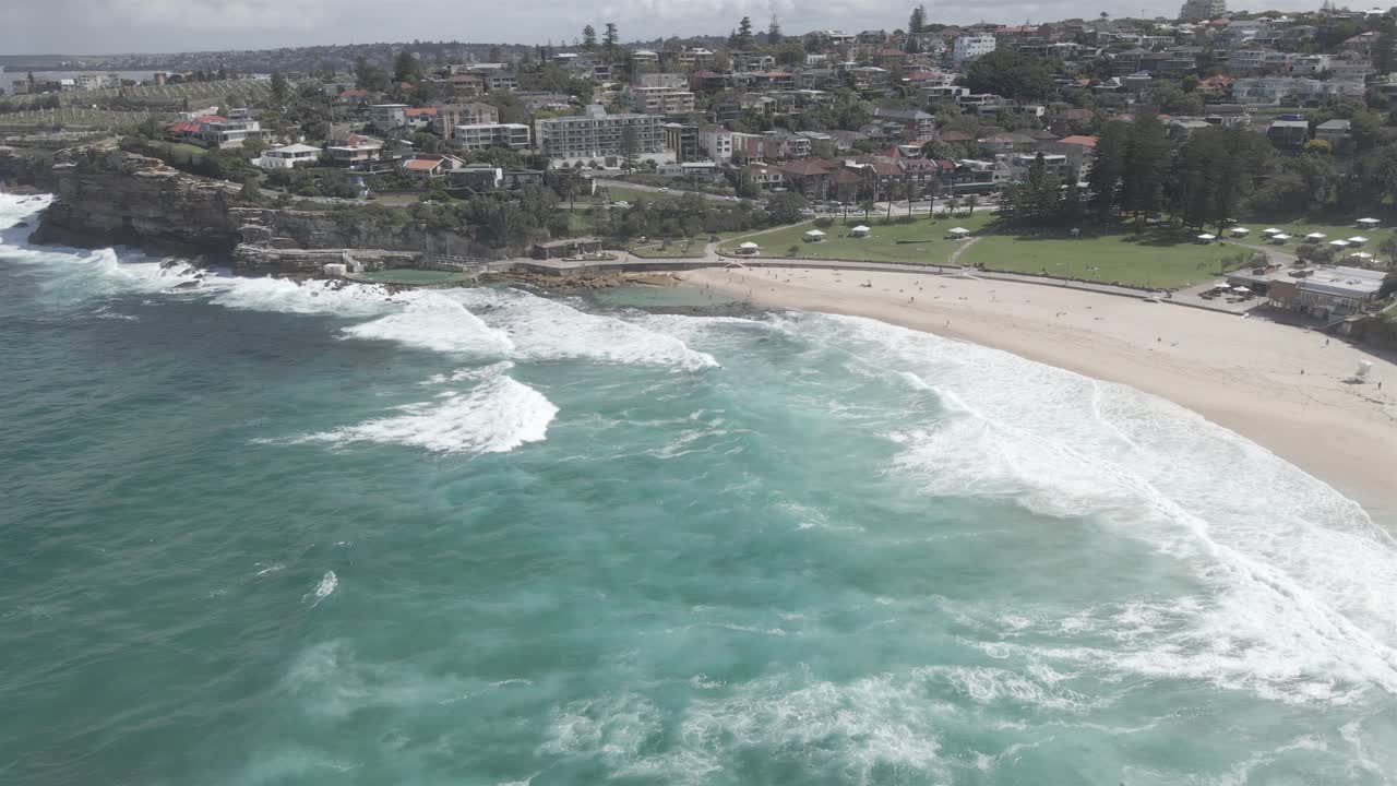 View Along The Foreshore Of Bronte Beach With Turquoise Sea And Fine Sandy Beach In Eastern Suburbs, Sydney, New South Wales, Australia - aerial drone shot