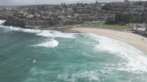 Vista-A-Lo-Largo-De-La-Playa-De-Bronte-Con-Mar-Turquesa-Y-Playa-De-Arena-Fina-En-Los-Suburbios-Del-Este,-Sydney,-Nueva-Gales-Del-Sur,-Australia---Toma-Aérea-De-Drones