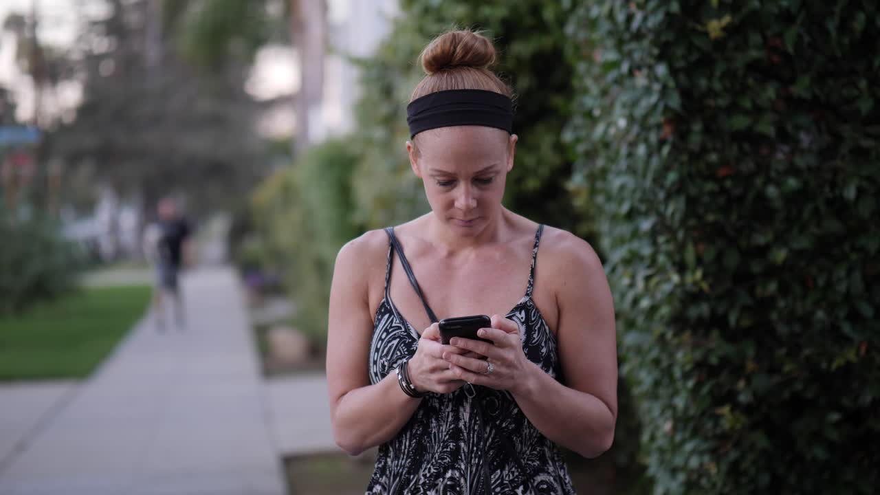 Redhead Woman using her Smartphone on a Street Corner