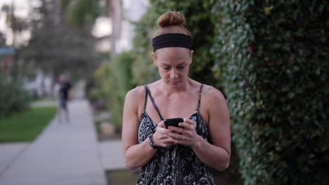 redhead woman using her smartphone on a street corner