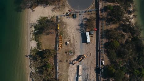 un sitio de construcción cerca de una ciudad importante que realiza obras de infraestructura en una península costera para instalar servicios a una población en crecimiento