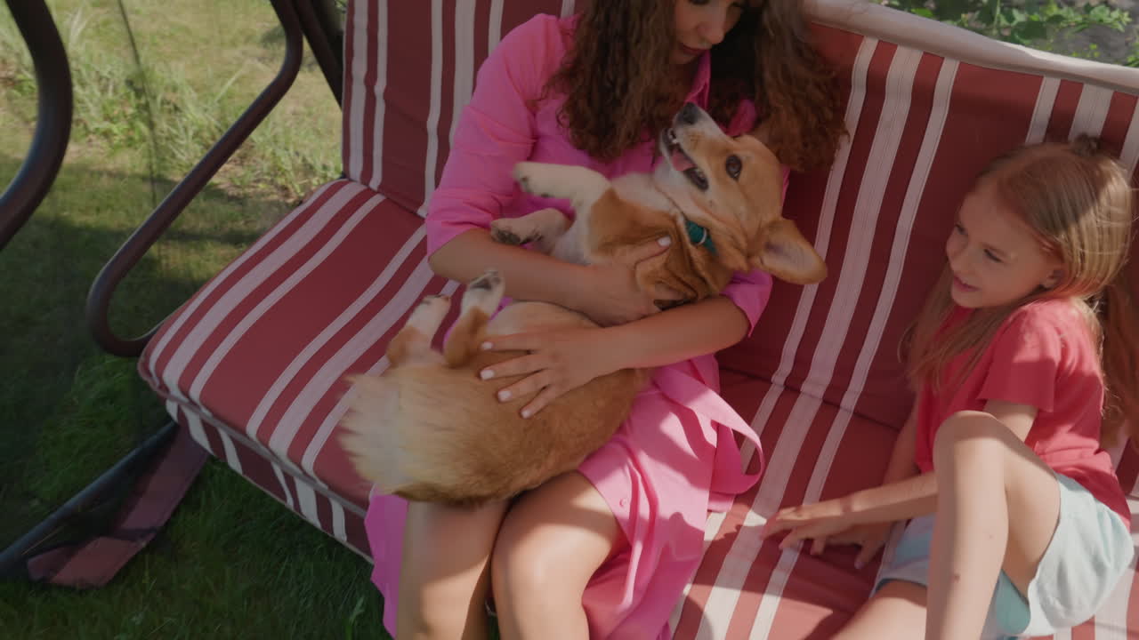 Family Enjoying Sunny Backyard Day, Youngsters And Puppy Bonding In Cheerful Garden Environment, Little Ones And Their Corgi Engaging In Playful Affection Amid Summer Garden Background