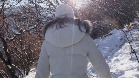화창한 날 겨울 동안 눈 덮인 산을 걷는 여성의 영감을 주는 장면