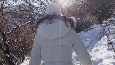 inspirational footage of woman walking in a snowy mountain during the winter on a sunny day