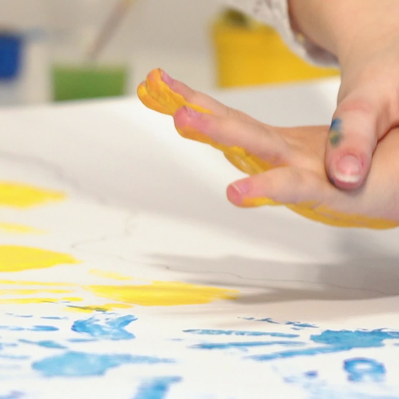Child making hand prints on paper. Early childhood education. Little painter.