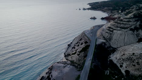 Paphos-De-La-Roca-De-Afrodita:-Carretera-Costera-Que-Se-Curva-A-Lo-Largo-De-Un-Acantilado,-Puesta-De-Sol,-Vista-Al-Mar,-Perspectiva-Aérea