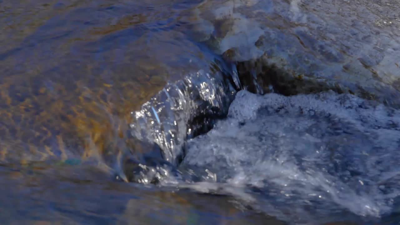 Primo piano al rallentatore di un ruscello che scorre in acqua corrente in mezzo alla natura