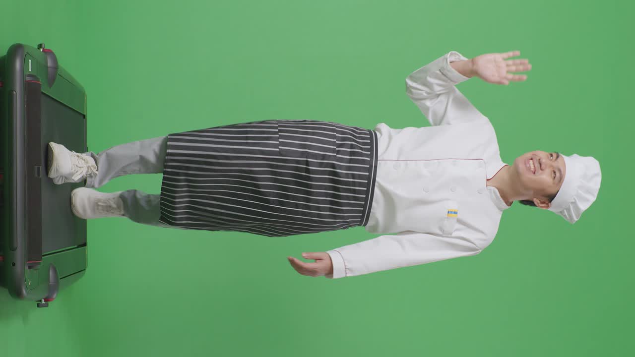 아시아 남자의 몸이 가득한 셰프가 트레드밀을 고 녹색 스크린 배경 스튜디오에서 손을 흔들고 있습니다.