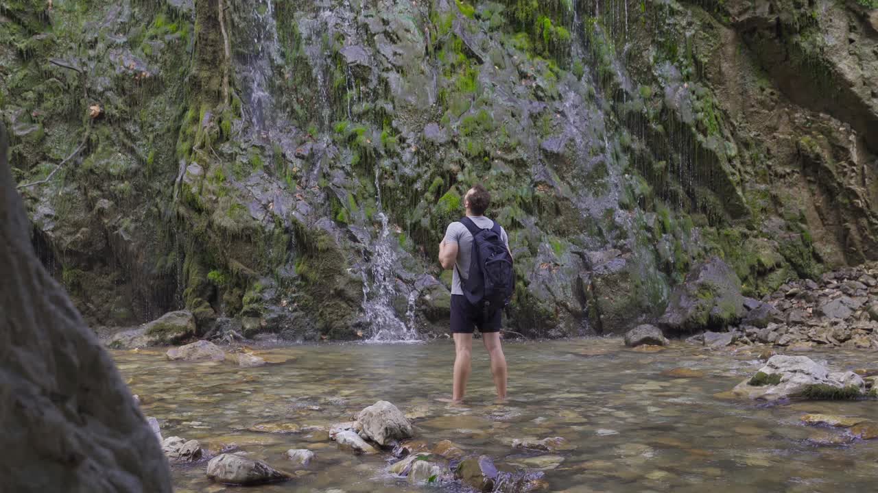 un joven libre frente a una cascada.
