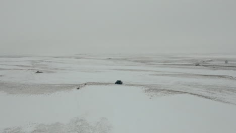 slow orbiting aerial of utv side by side in middle of barren snowy prairie, 4k