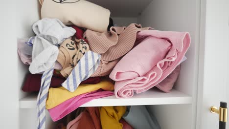 messy wardrobe shelf with pile of clothes