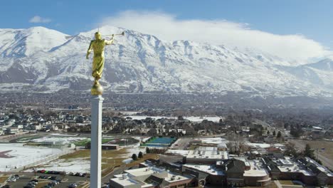 Beautiful-Angel-Moroni-Statue-atop-LDS-Mormon-Temple-in-Utah-Mountains,-Aerial-Flight