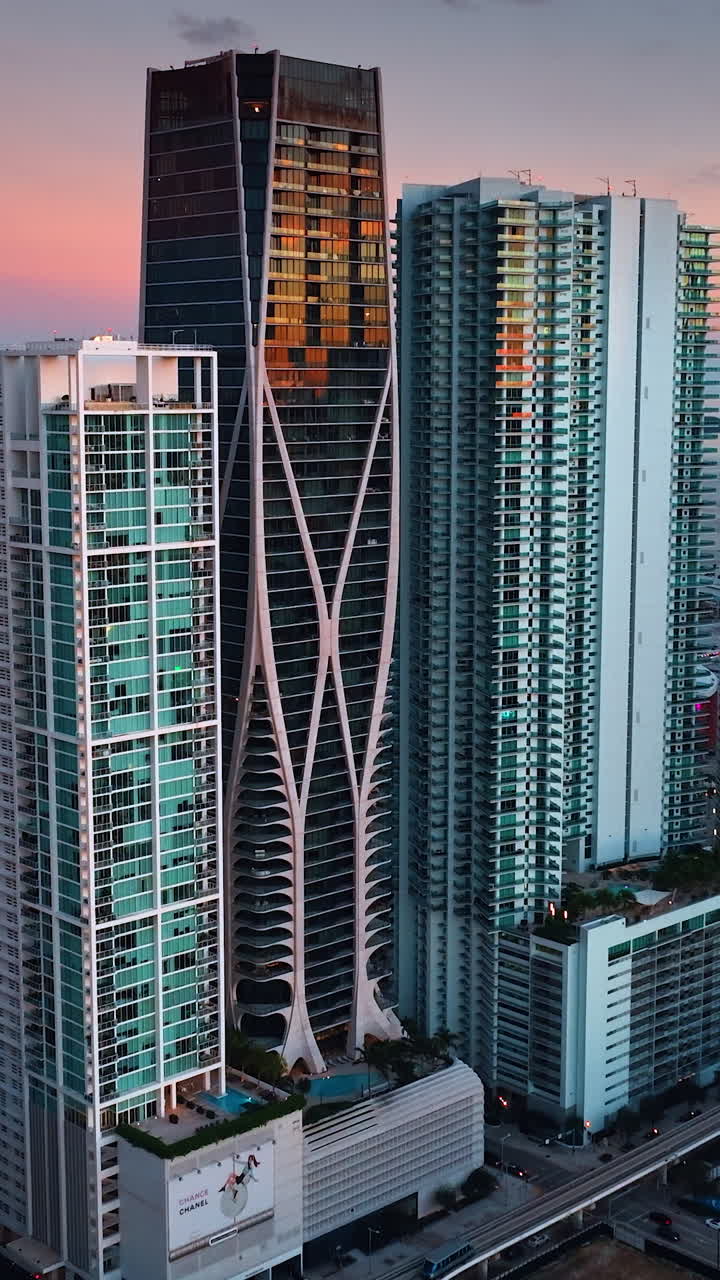 Approaching the group of skyscrapers standing close to each other. High-rise building in rays of setting sun in Miami, Florida, United States. Vertical video