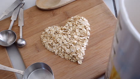 A-pile-of-oats-grain-cereal-animated-into-a-heart-shape-with-kitchen-utensils-for-a-healthy-oatmeal-breakfast-TOP-DOWN