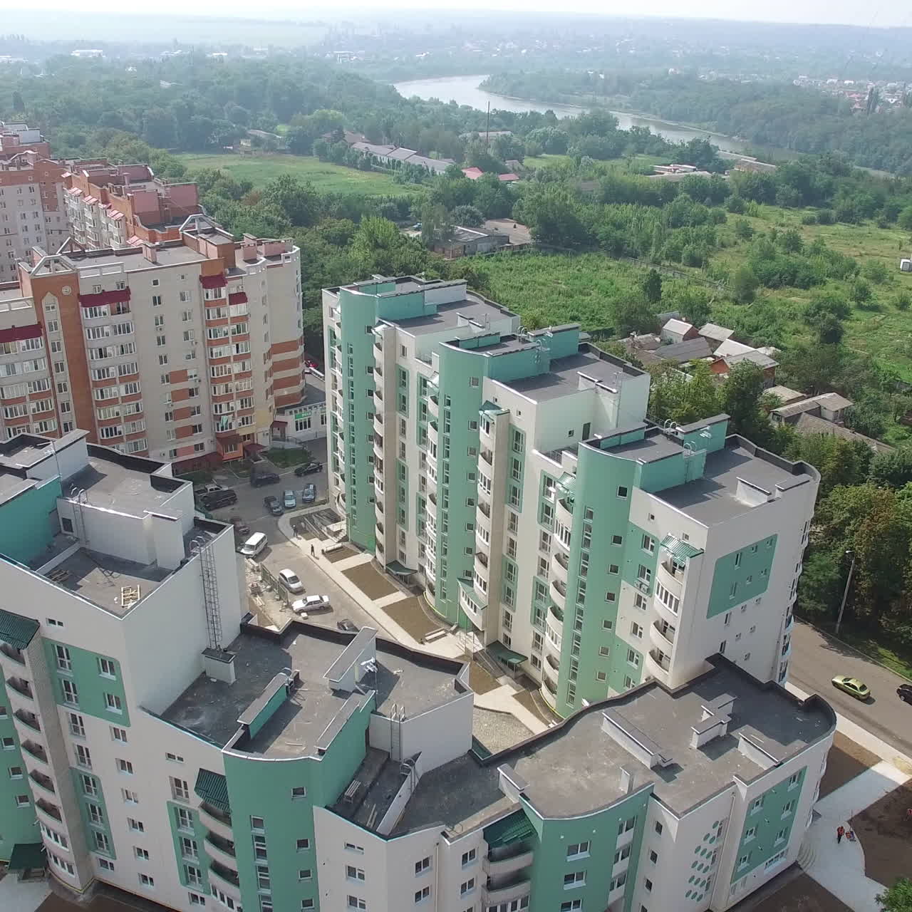 Aerial shot approaching a complex of high rise public housing apartments in front of a nature park. Motion camera back