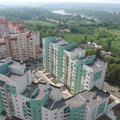 aerial shot approaching a complex of high rise public housing apartments in front of a nature park. motion camera back