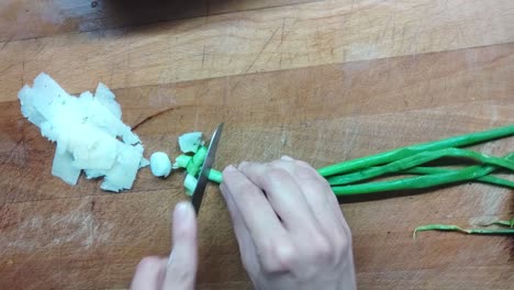 food preparation: cutting fresh onion on a wood surface for a green salad plate