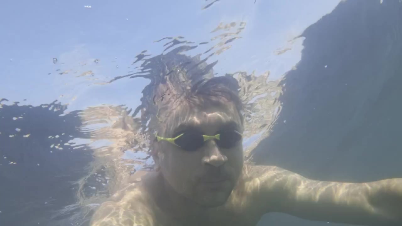Uomo che nuota sott'acqua, godendosi un'attività estiva in acqua limpida. La luce del sole crea bellissime rifrazioni sulla superficie.