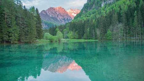 Schöner-Jezersko-see-Mit-Sonnigen-Alpenbergen-Im-Hintergrund,-Umgeben-Von-Bäumen