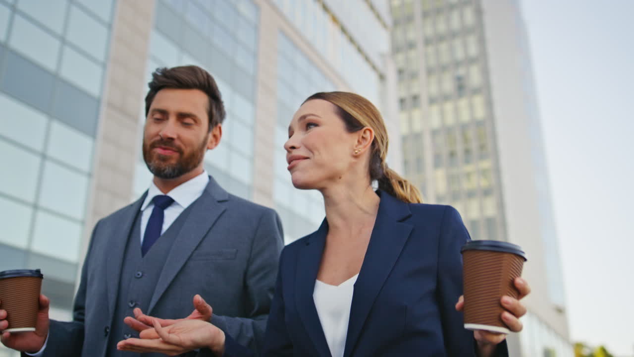compañeros de trabajo riendo caminando por el distrito urbano con café de cerca. colegas felices