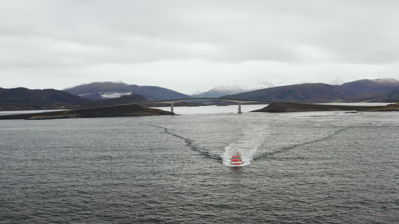 노르웨이의 배경에 storseisundet 다리가 있는 노르웨이 바다를 순항하는 보트