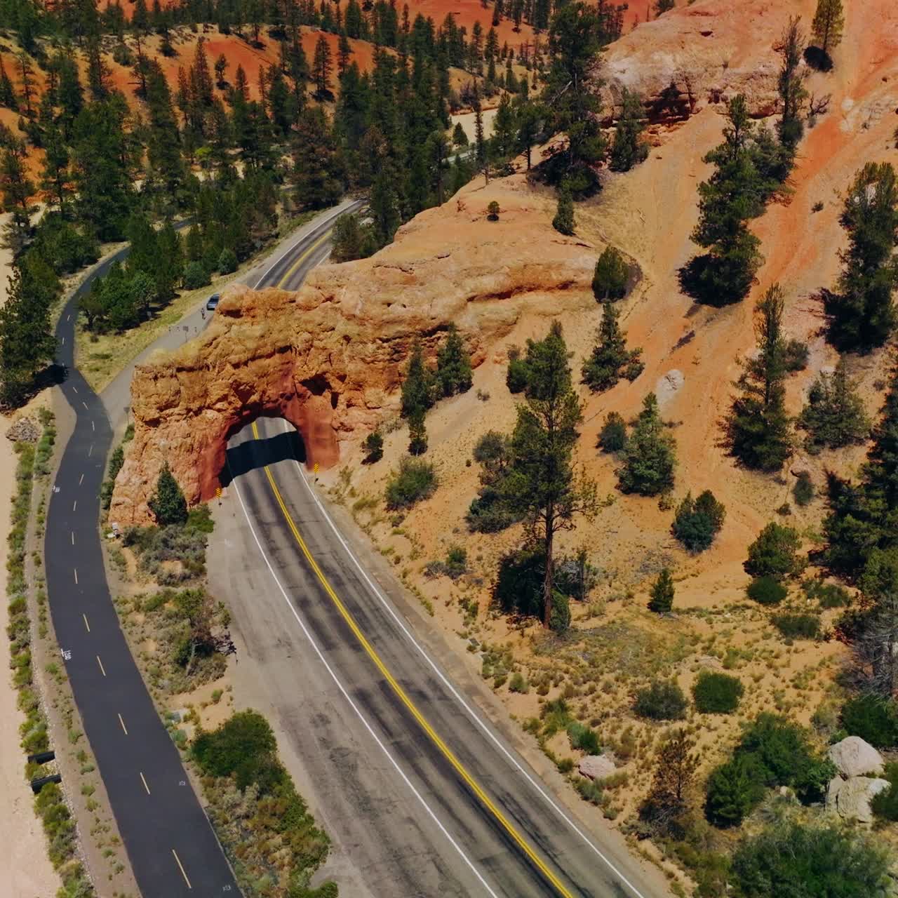Rocky arch over the motorway in National park in United States. Bright sunny day in Arches Canyons, Utah. Aerial view
