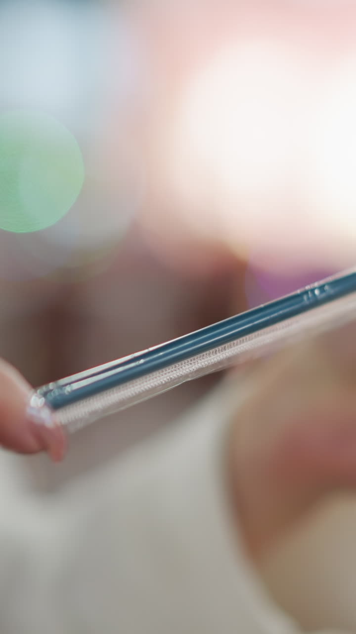 primer plano de manos quitando cuidadosamente una paja negra de su funda protectora en un entorno interior moderno, con un fondo suavemente borroso con luces bokeh cálidas