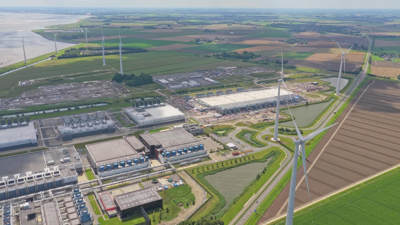 Aerial drone of hyperscale data centers with wind turbines in Dutch landscape