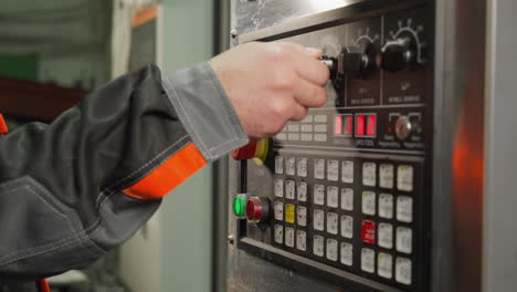 worker's hand adjusting settings on a cnc machine's control panel with digital display