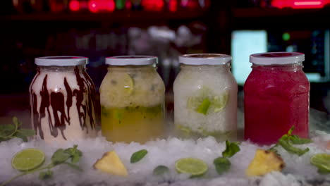 dry ice reveal of colourful frozen smoothie jars on bar. dolly forward, slow motion