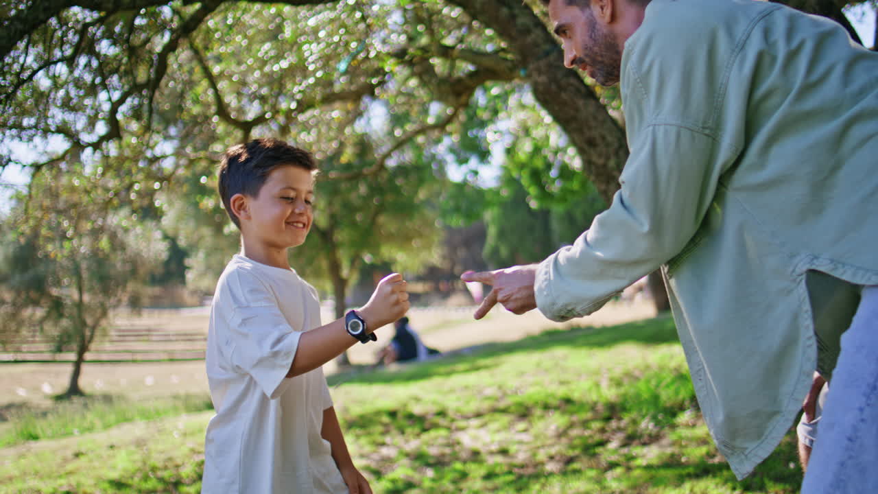 Carefree dad son playing rock-paper-scissors at garden. Happy child winning game