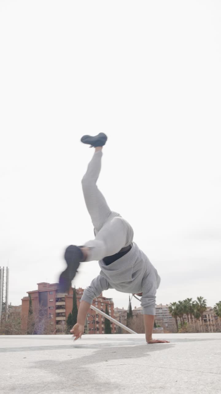 Breakdancer performing handstand and flip on rooftop