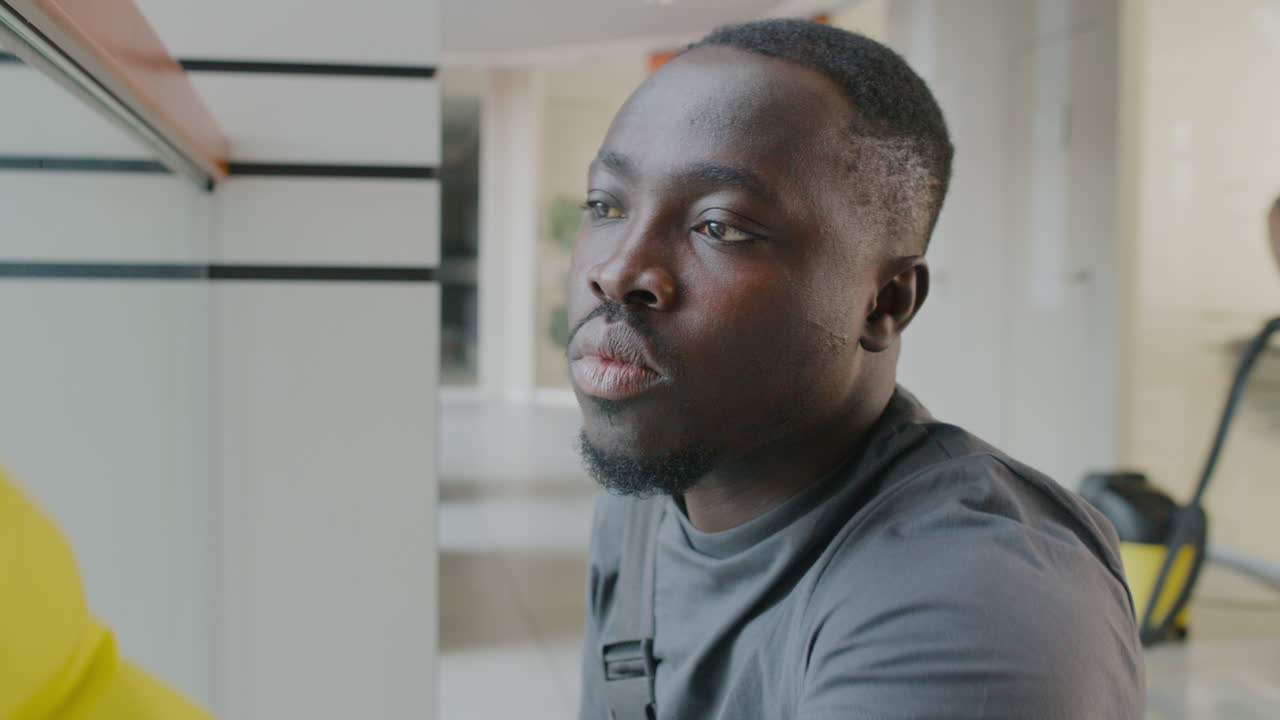 사무실 건물 내부의 크리스탈 벽을 청소하는 청소부 1의 클로즈업 보기