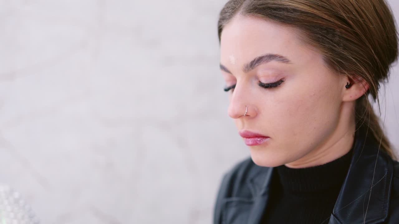 A young woman applies makeup to her face using a beauty sponge