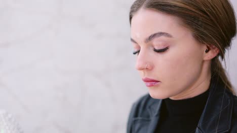 a young woman applies makeup to her face using a beauty sponge