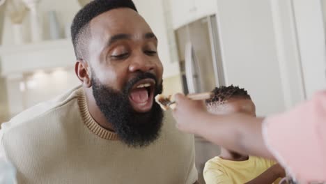 happy african american father with son and daughter enjoying meal in dining room, slow motion