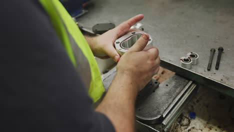 Close up detail of hands of a Caucasian male factory worker standing at a workbench and working on a