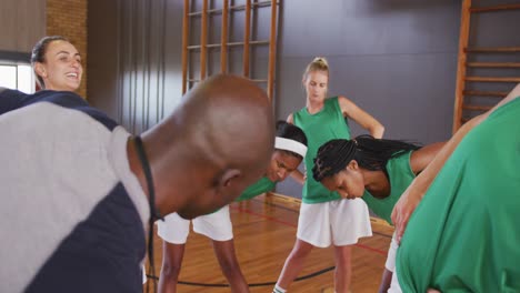 equipo de baloncesto femenino diverso estirando con entrenador masculino