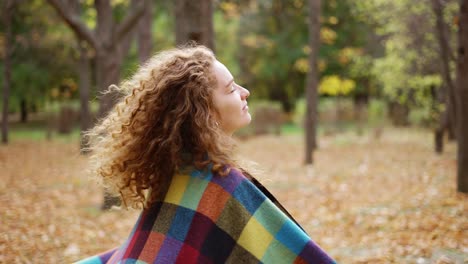 mujer en un parque o bosque de otoño dorado cubriéndose en cuadros girando alrededor