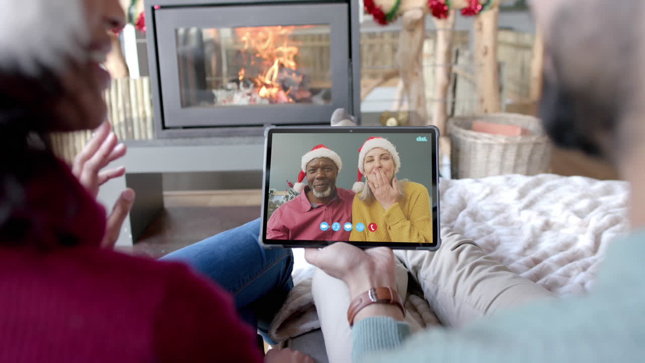 Due coppie felici e diverse in videochiamata di Natale su tablet, al rallentatore