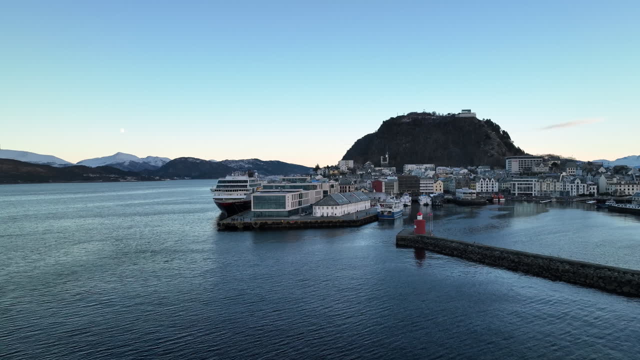 Norway 4K Aerial of &Aring;lesund in winter slowly pushing into the harbour with beautiful sunset in the background