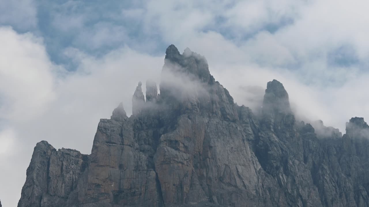 Sharp and rocky mountain range in the Swiss Alps, moving clouds pass over the ridges