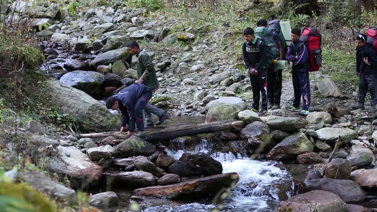 Himalayan mountaineers making a temporary bridge over the river ganges, to cross the river. Group on mountaineers on their way to destination.In Upper Himalayas, Uttarakhand, India.