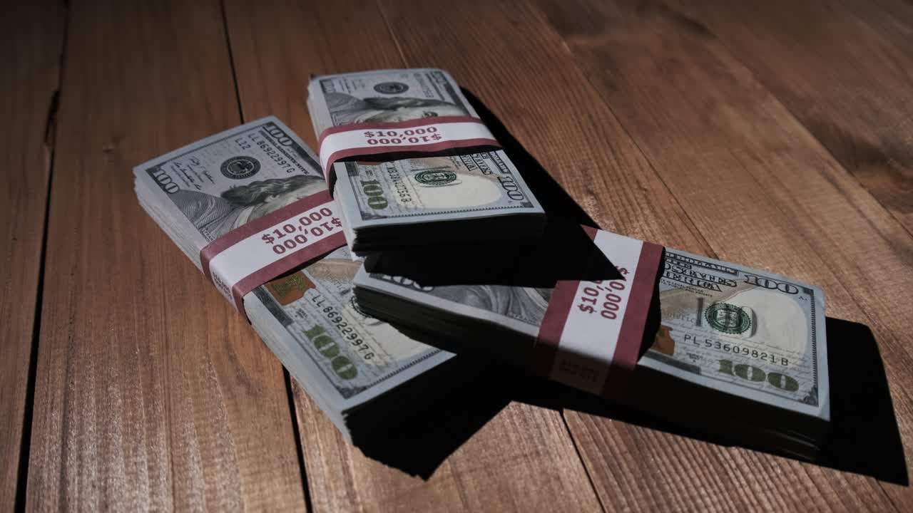 Three Stacks of 10000 American Dollars Banknotes in Bundles Lie on Wooden Table